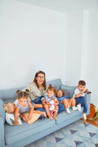 Mãe sentada no sofá com vários filhos