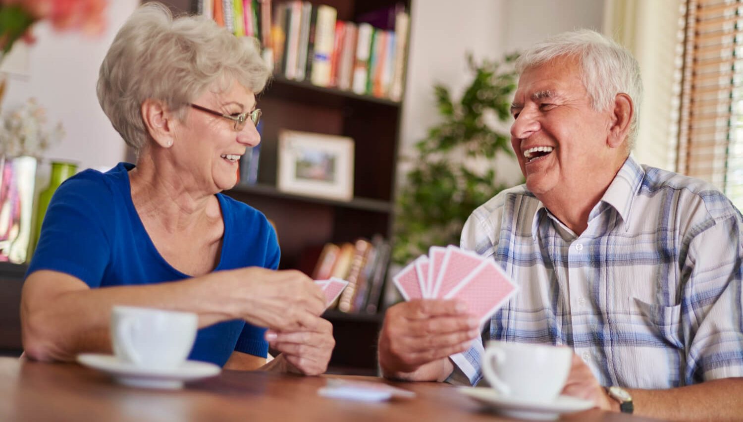 Casal de velhinhos a rir juntos e a jogar às cartas