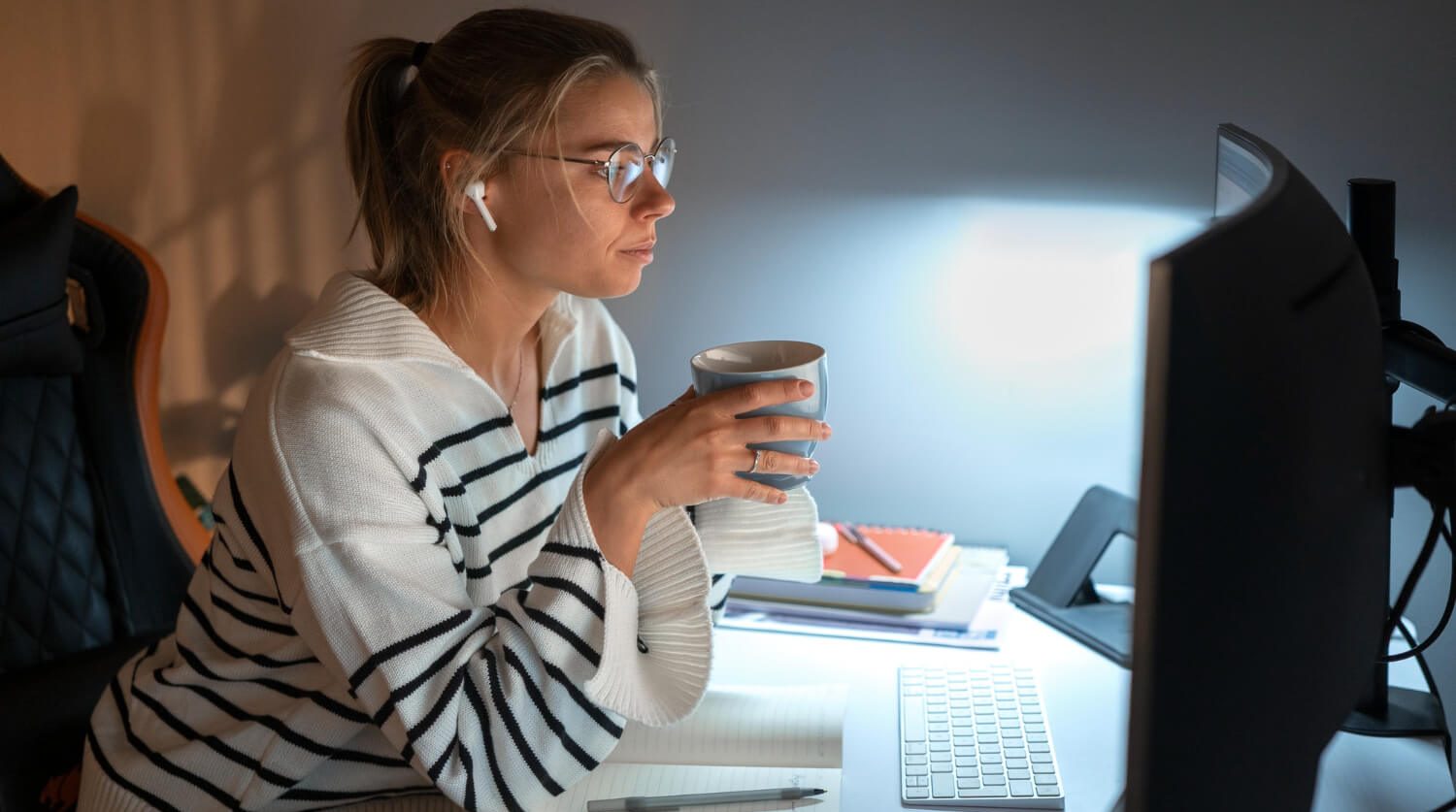 senhora a trabalhar à noite no computador e a beber um chá