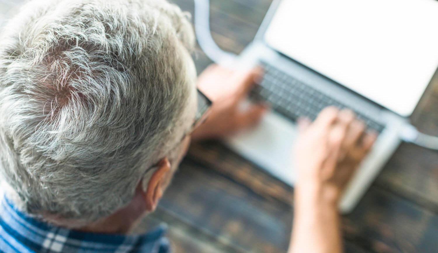 Senhor com cabelo grisalho a usar um computador