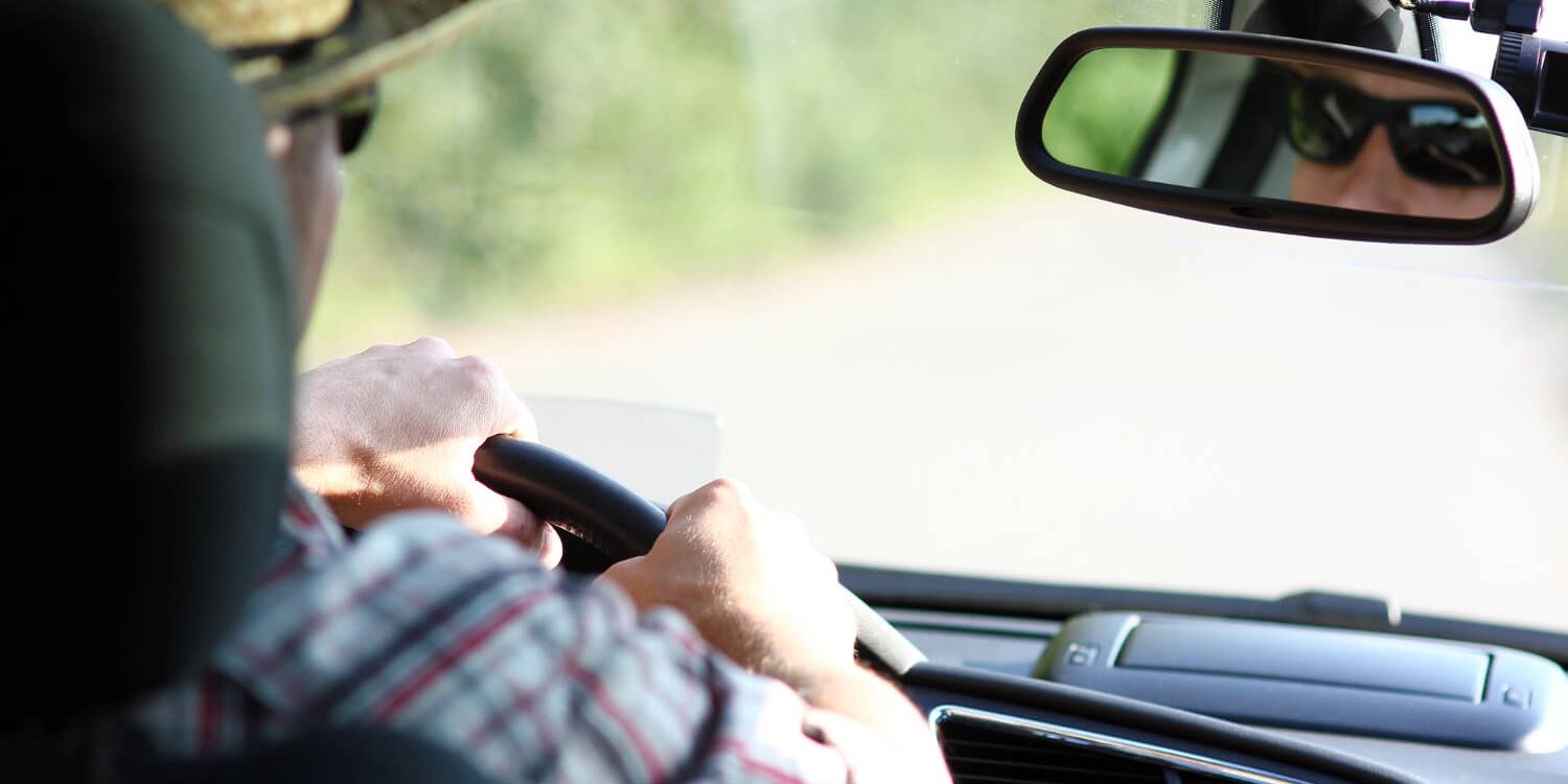 Senhor a conduzir um carro importado