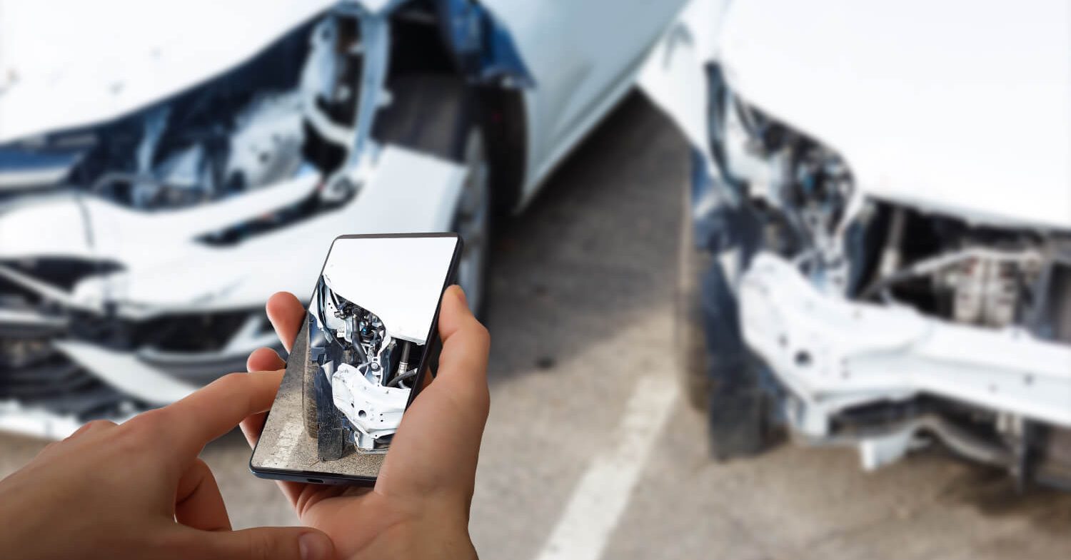 Pessoa a tirar fotos a um carro danificado num acidente