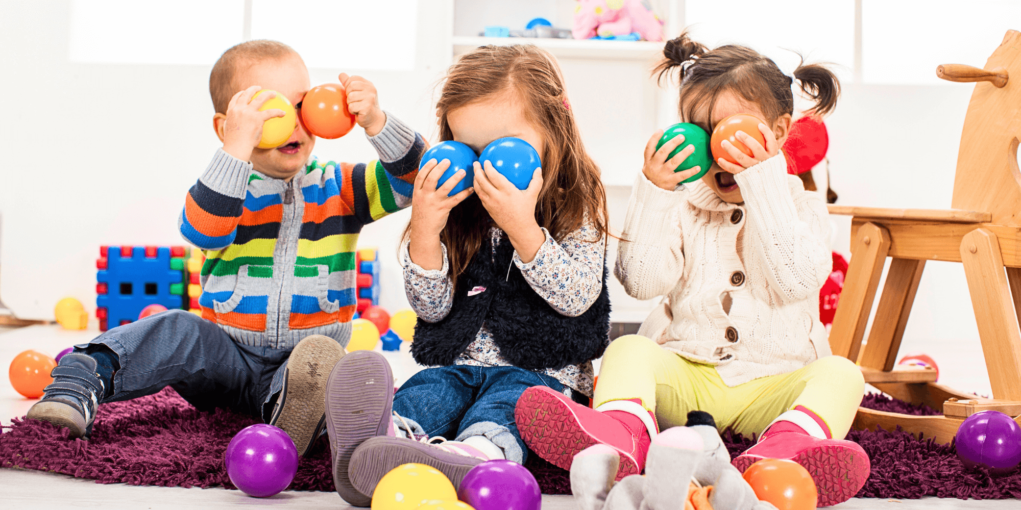 3 crianças a tarpar os olhos com bolas de borracha e divertidas na creche
