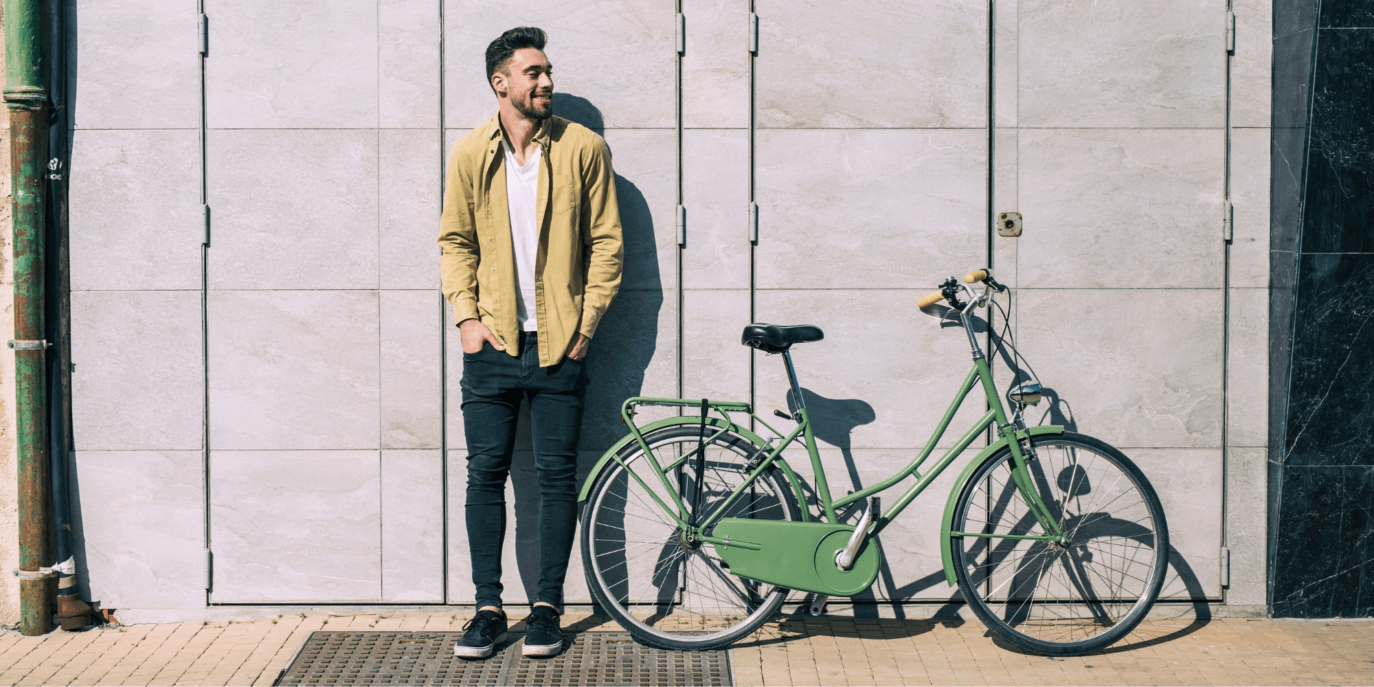 Rapaz encostado a uma parede com uma bicicleta verde