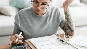 Mulher calculando e preenchendo impostos com calculadora e documentos fiscais — gestão financeira e declaração de impostos em Portuga