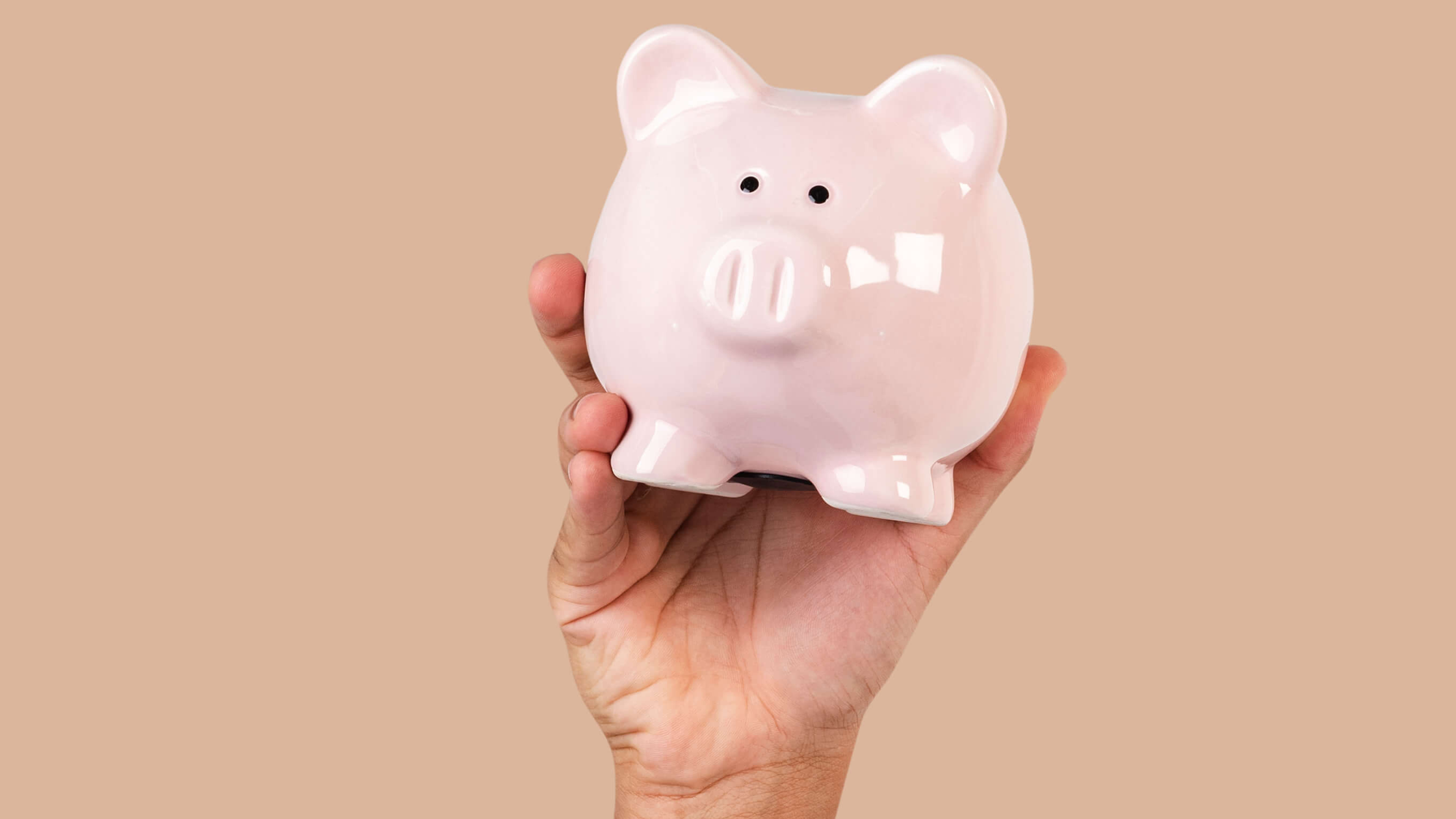 Mealheiro cor-de-rosa sobre mesa com moedas e notas, simbolizando poupança e gestão financeira no fim do ano em Portugal.