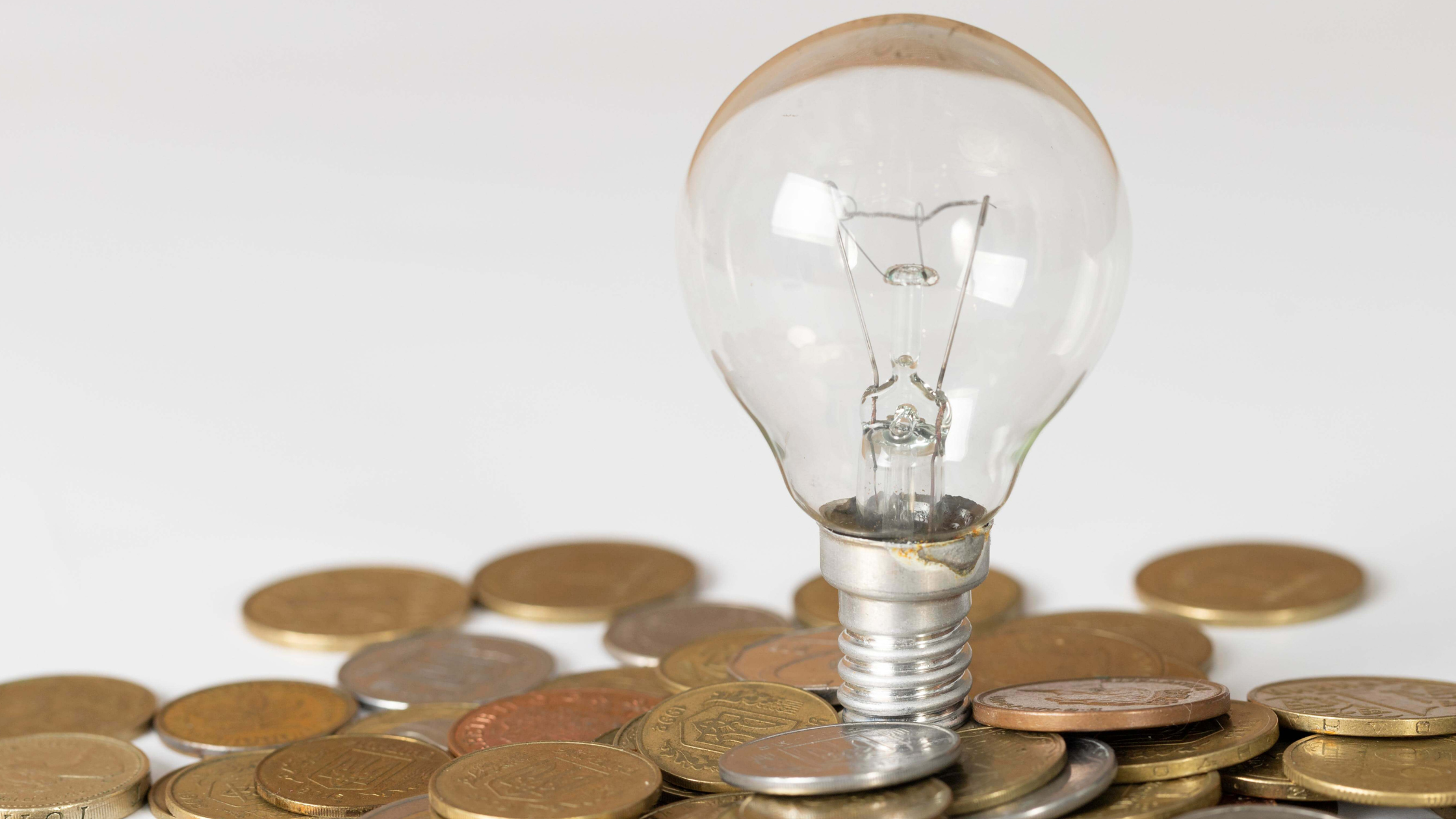 Imagem ilustrativa de uma lâmpada com moedas, representando ideias de poupança energética e gestão financeira familiar.