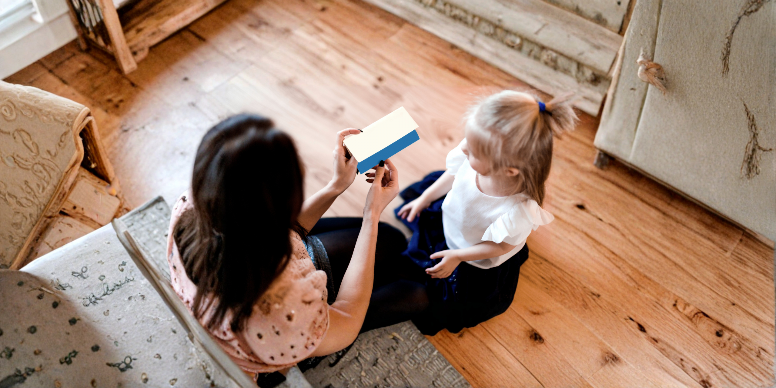 Mulher sentada nas escadas a mostrar um cartão de identificação a uma criança, em ambiente doméstico.