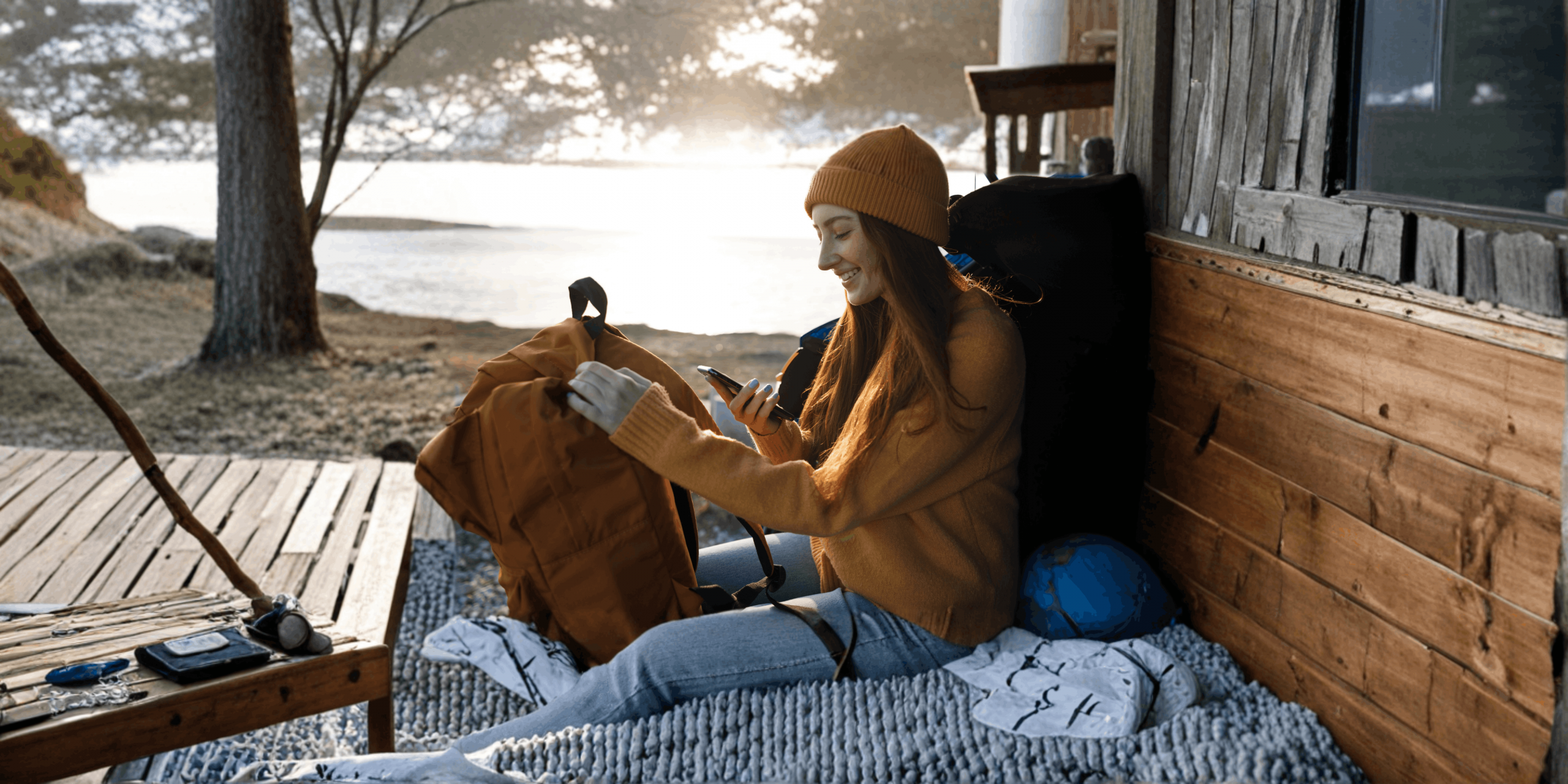 Viajante a preparar a mochila enquanto consulta o telemóvel, simbolizando planeamento de viagem e acesso a assistência consular no estrangeiro com a app Registo do Viajante.