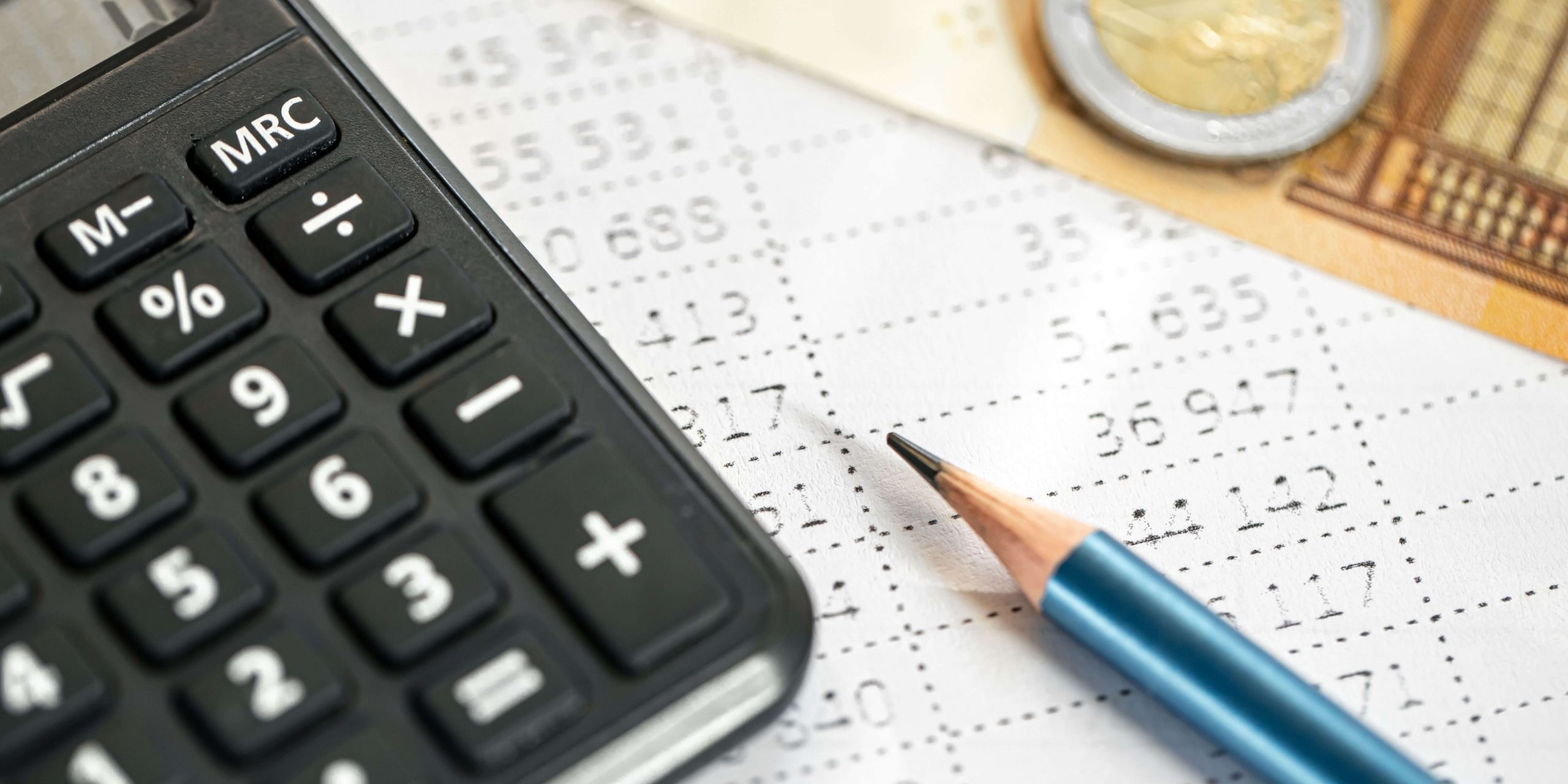 Calculadora, lápis e documentos financeiros usados para preparar e entregar a declaração de IRS 2026 em Portugal.