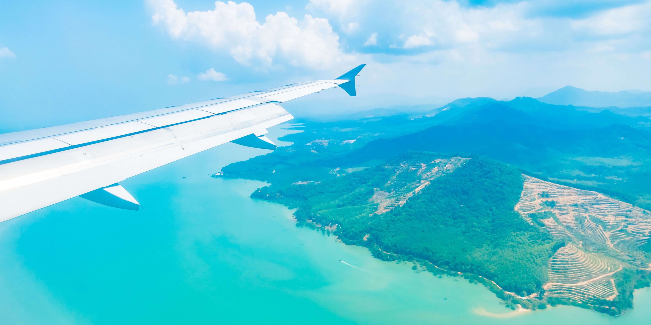 Vista aérea a partir de um avião sobre o mar e uma ilha, ilustrando as viagens aéreas entre o Continente, a Madeira e os Açores no contexto do Subsídio Social de Mobilidade.