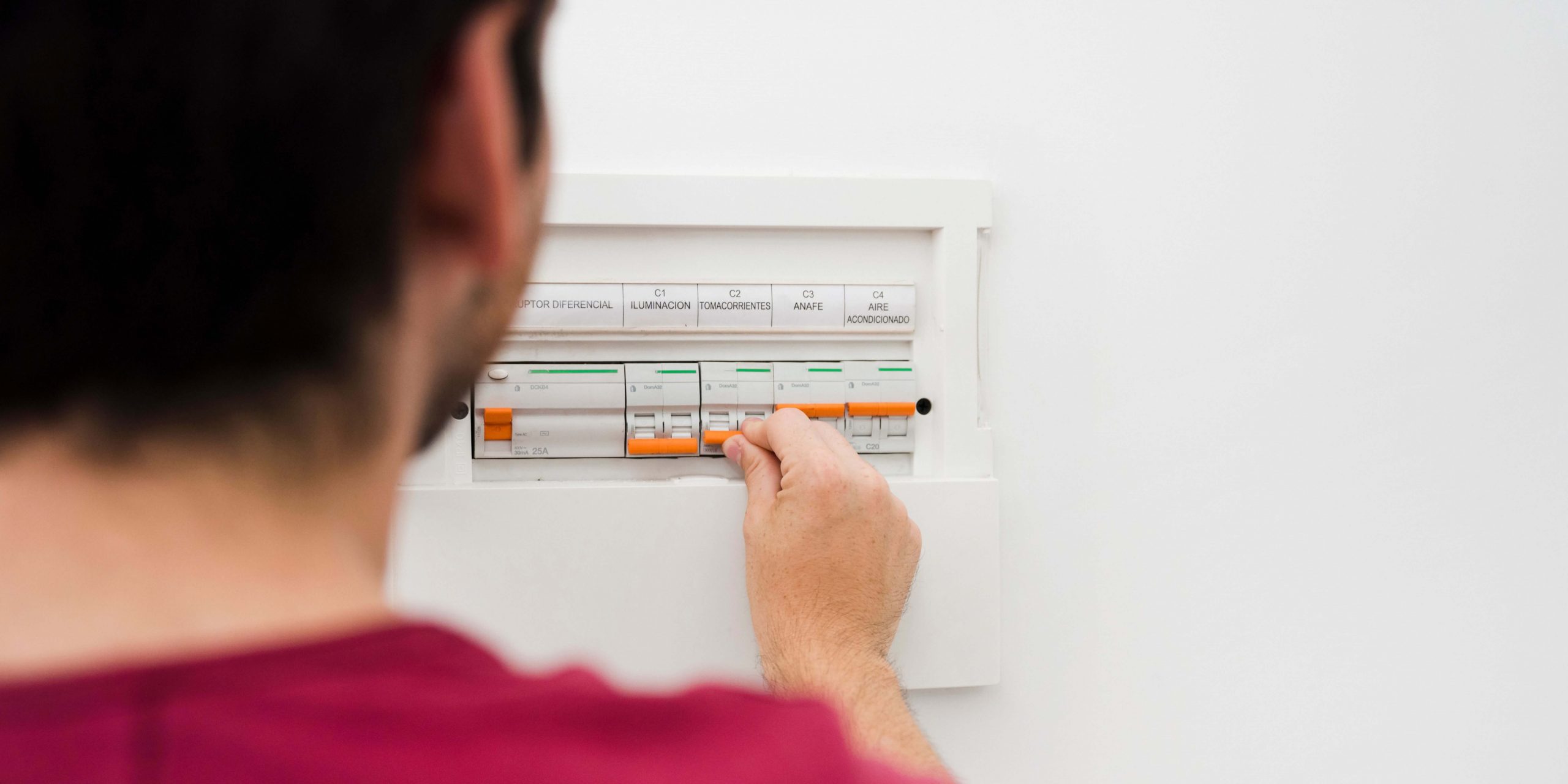 Homem verifica o quadro elétrico de casa, imagem ilustrativa sobre consumo de eletricidade, leitura do contador da luz e controlo da fatura para evitar estimativas.