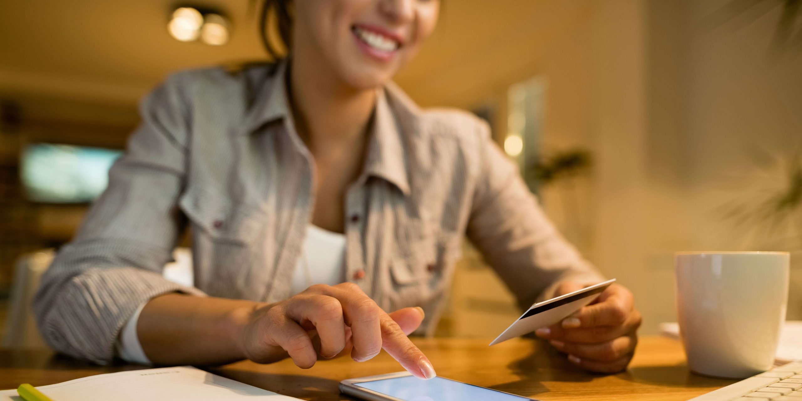 Mulher a utilizar um telemóvel e um cartão bancário para efetuar um pagamento online, representando o pagamento de contribuições à Segurança Social em 2026.