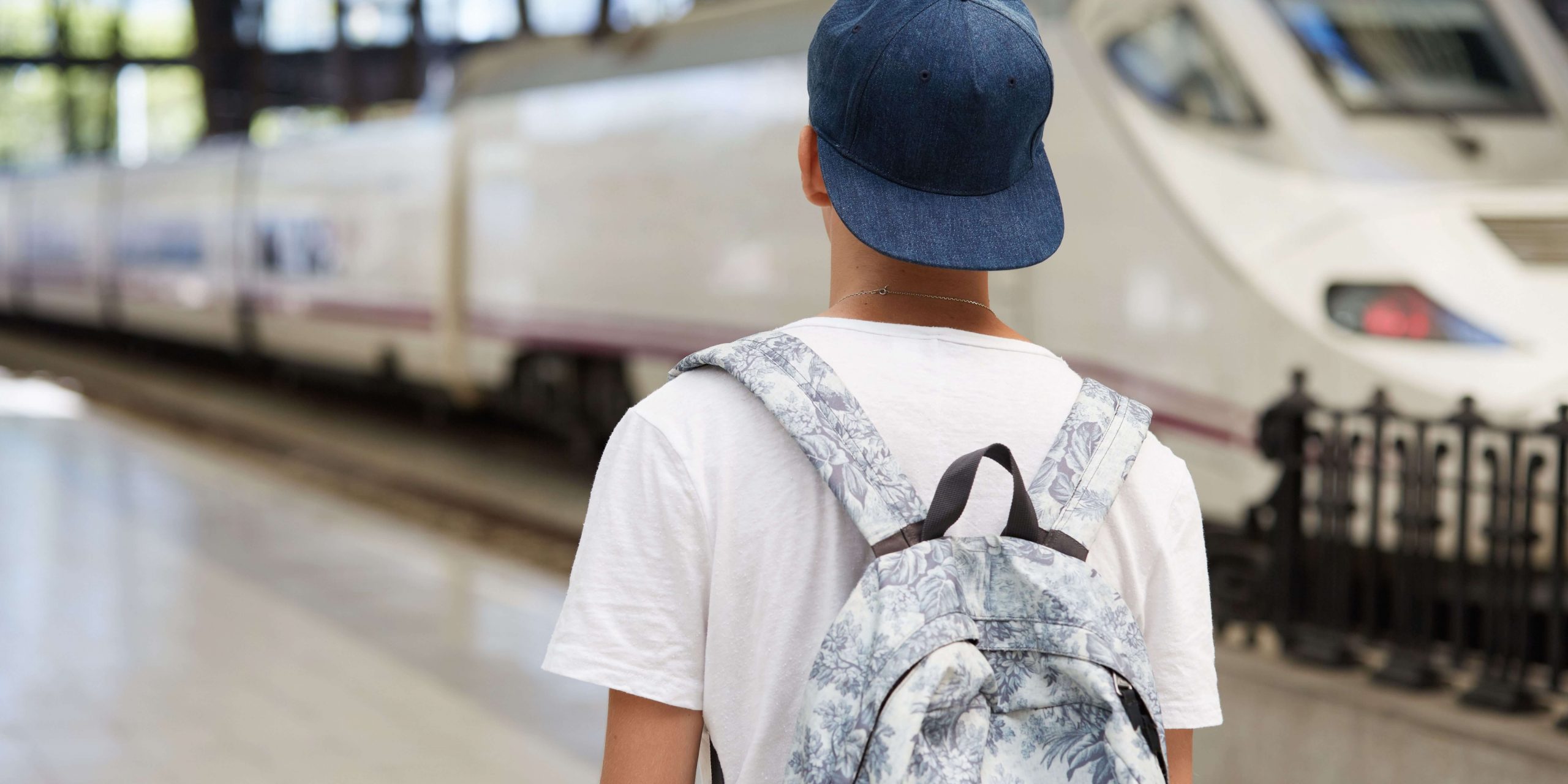 Jovem com mochila numa estação junto a um comboio, alusivo aos vouchers do ANDA Conhecer Portugal 2026.
